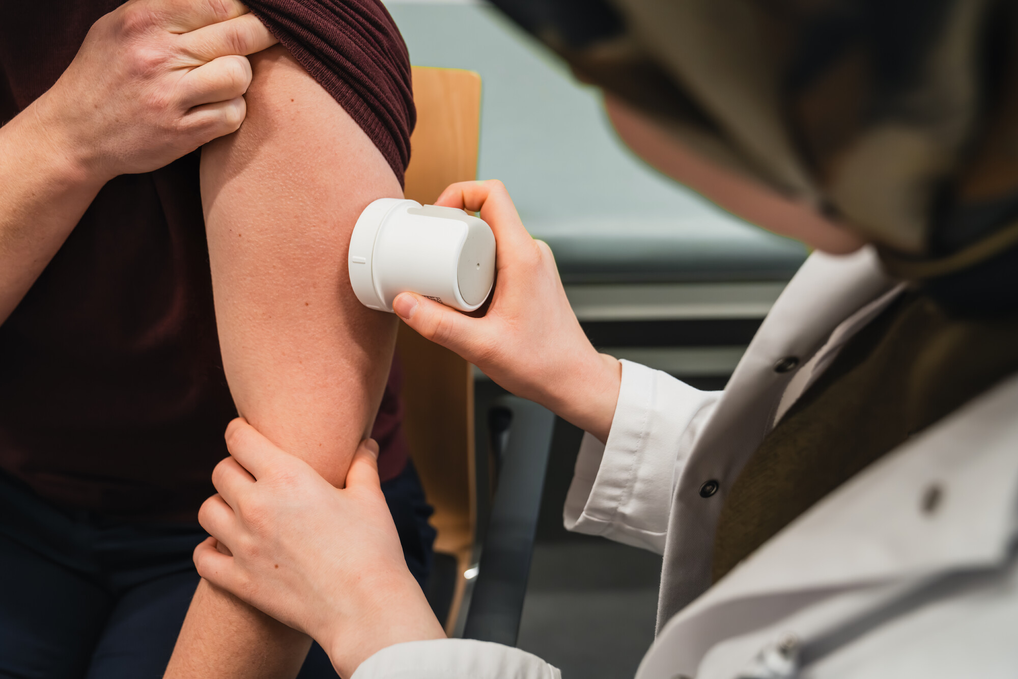 CGM wird von einer medizinischen Fachkraft am Arm einer Patientin angebracht.